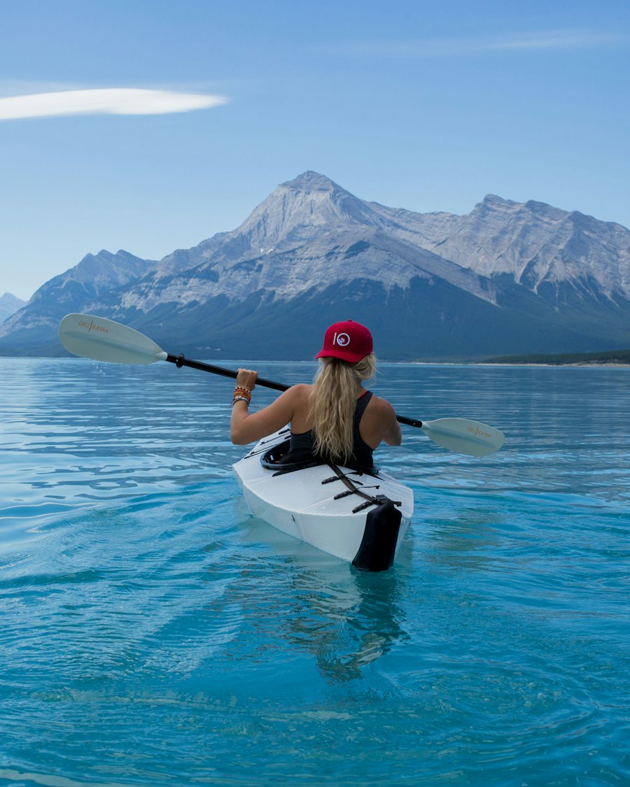 A paddler in a white sea kayak heading toward the mountains