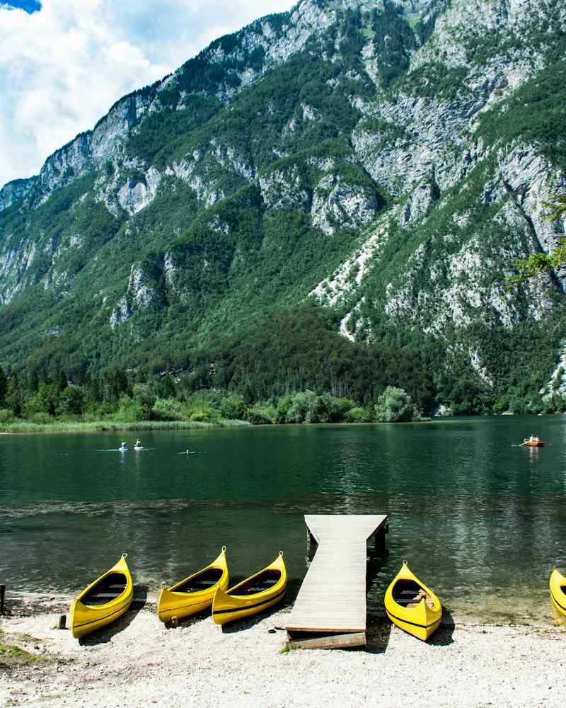 Yellow kayaks pulled up on a beach below the mountains